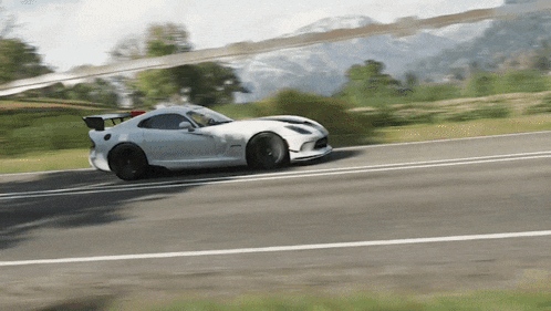 a white sports car is driving down the road