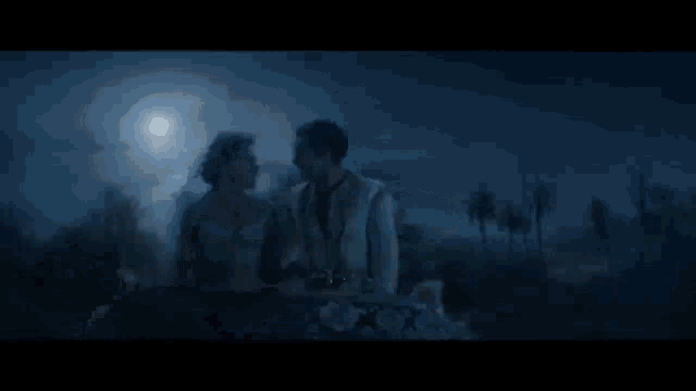 a boat is floating on top of a body of water at night with a full moon .