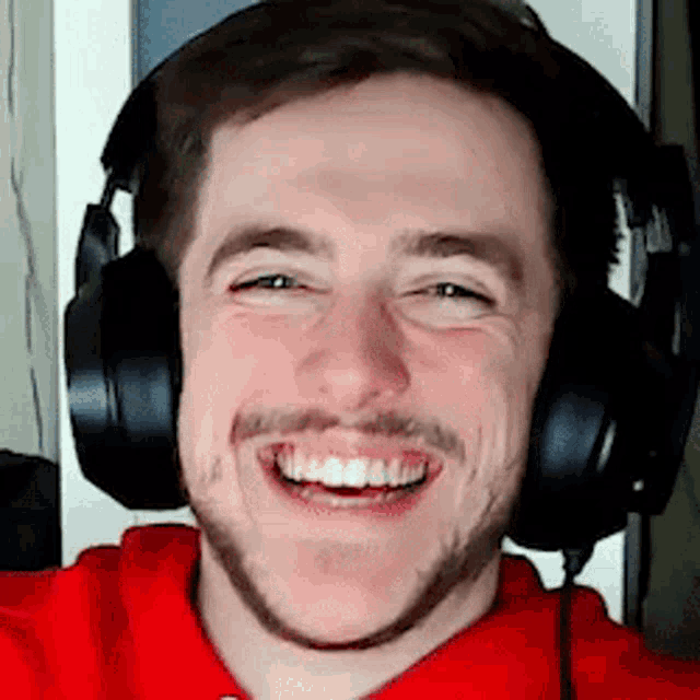 a man with a beard is wearing headphones and smiling for the camera .