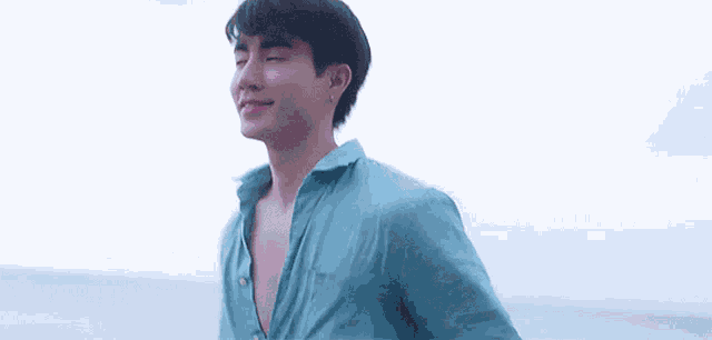 a man in a blue shirt is holding a woman 's hand on the beach .