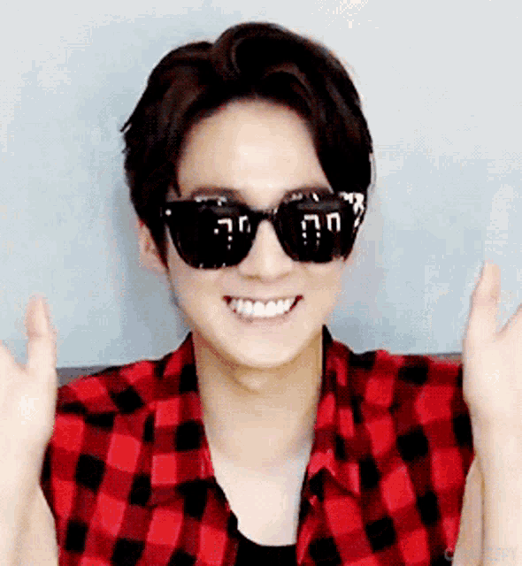 a young man wearing sunglasses and a red plaid shirt