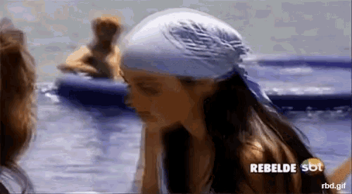 a woman with a bandana on her head is standing in the water with a rebelde sbt logo in the corner