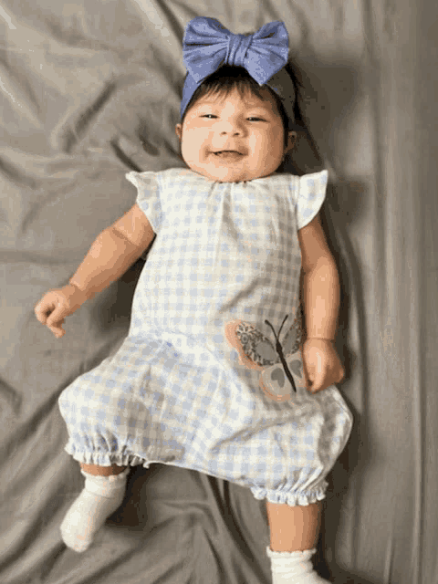 a baby wearing a blue headband and a blue dress with a butterfly embroidered on it