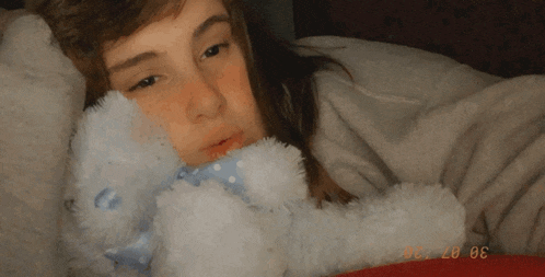 a girl is laying in bed with a teddy bear and the date 30 07 20 is visible