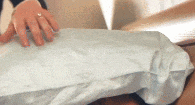 a person with a ring on their finger is holding a pillow .