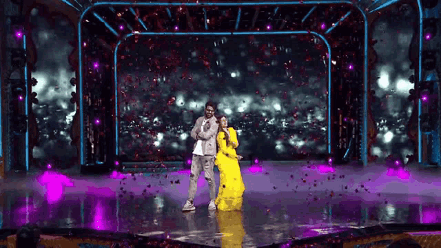 a man and a woman are dancing on a stage with confetti falling from the ceiling .