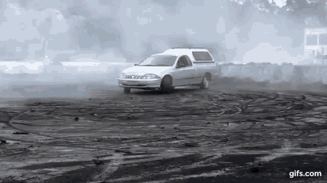 a white truck is driving down a dirt road .
