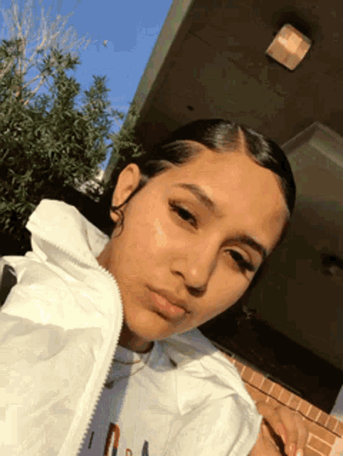 a girl wearing a white jacket is taking a selfie .