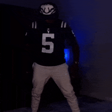 a man wearing a number 5 jersey is standing in front of a blue background .