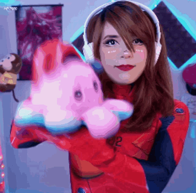 a woman wearing headphones holds a pink stuffed animal with the number 02 on it