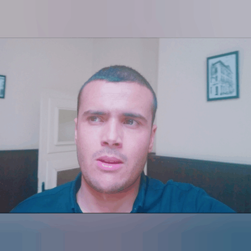 a man in a black shirt has a picture of a building hanging on the wall behind him