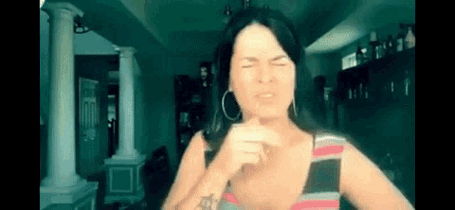 a woman with a tattoo on her arm is making a funny face with her eyes closed .