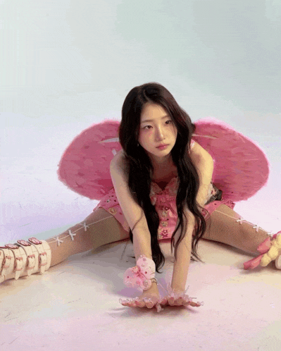 a woman in a pink dress and pink wings is sitting on the floor