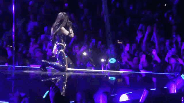 a woman is kneeling on a stage with a microphone in her hand