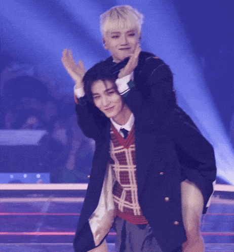 a man in a suit is carrying another man on his back on a stage