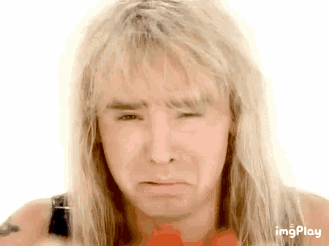 a man with long blonde hair is making a sad face with a white background
