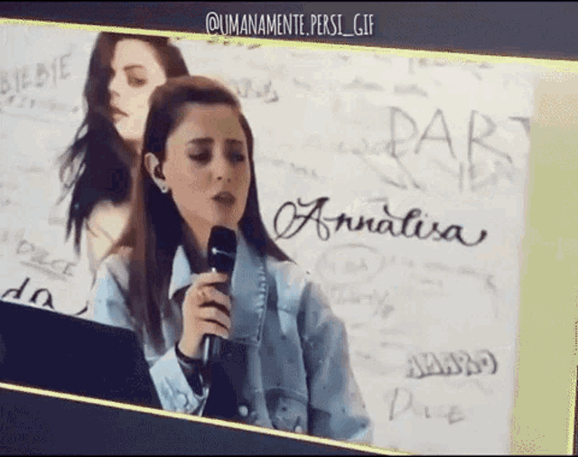 a woman is singing into a microphone in front of a wall that says ' annalisa ' on it