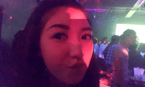 a woman stands in a dark room with a red light behind her