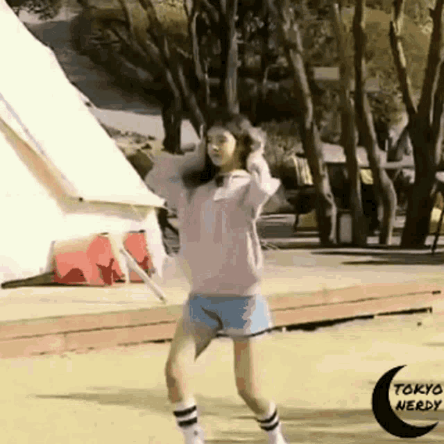 a girl is dancing in front of a tent with tokyo nerdy written on the bottom