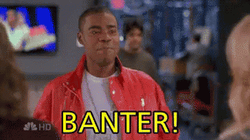 a man in a red jacket says banter in front of a tv