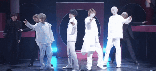 a group of young men in white clothes are dancing on a stage .