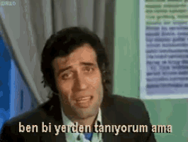 a man in a suit and tie is crying with the words ben bi yerden taniyorum ama written below him .