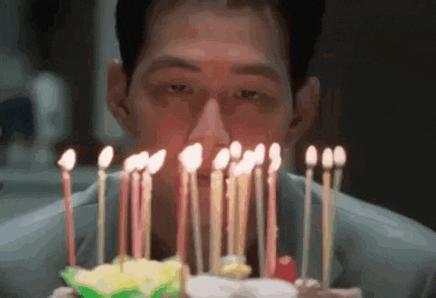 a man blowing out candles on a birthday cake .