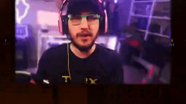 a man wearing headphones and glasses is wearing a t-shirt with the letter t on it