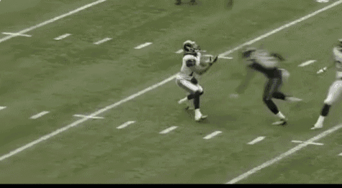 a football player is laying on the ground on the field while another player runs .
