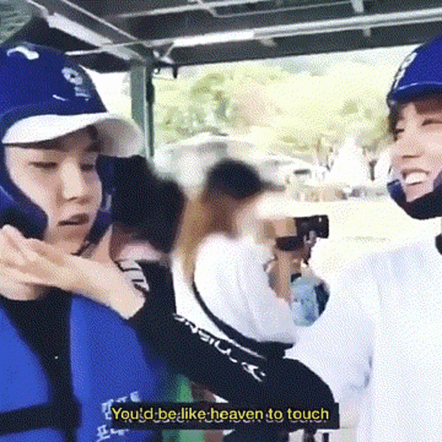 a man in a life jacket is talking to another man in a life jacket while wearing a helmet .