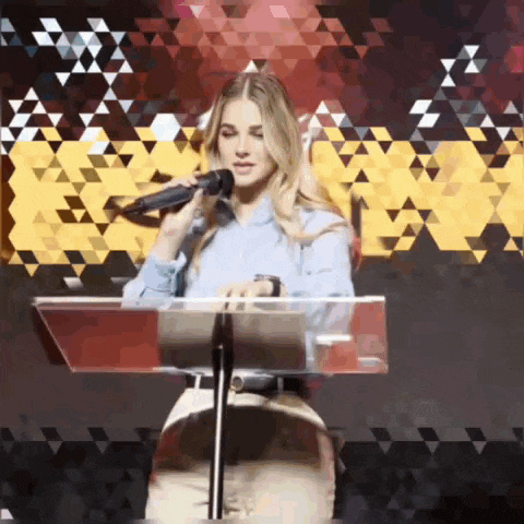 a woman is singing into a microphone while standing at a podium