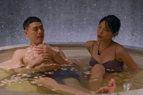 a man and a woman are sitting in a bathtub filled with flower petals .