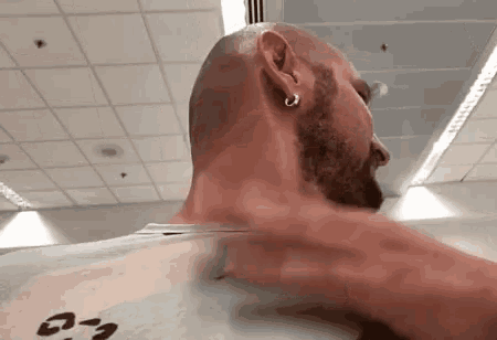 a man with a beard and earrings is laying down in a room .