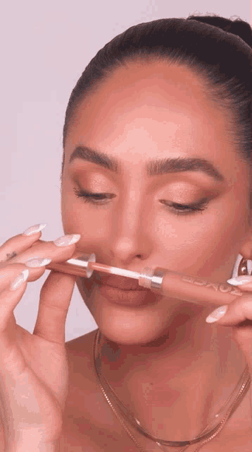 a woman is applying lipstick to her lips with a lipstick brush