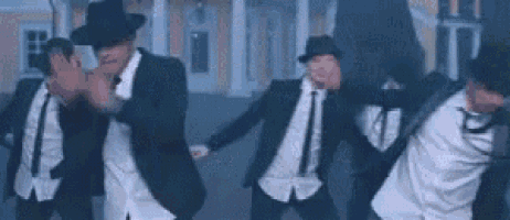 a group of men in suits and hats are dancing .