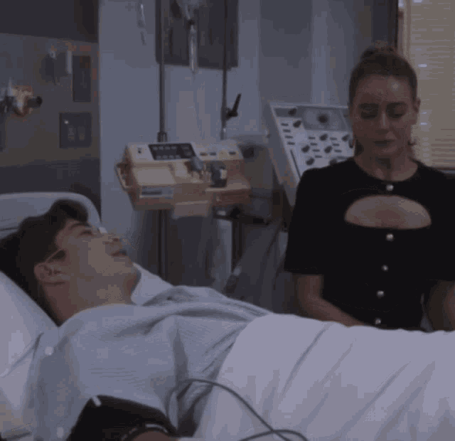 a man is laying in a hospital bed while a woman stands next to him