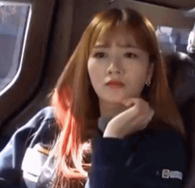 a woman with long red hair is sitting in a car and looking at the camera .