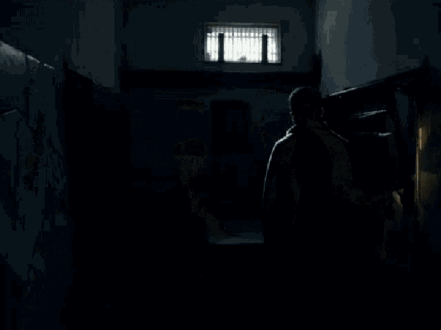 a man in a dark room with a shadow on the wall