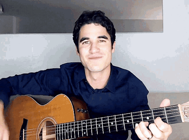 a man in a blue shirt plays a guitar