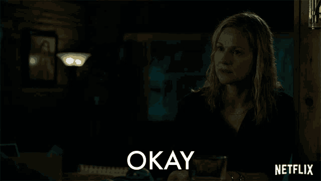 a woman sitting at a table with the word okay on the bottom