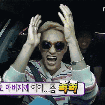 a man wearing sunglasses is screaming with his hands in the air while sitting in a car .