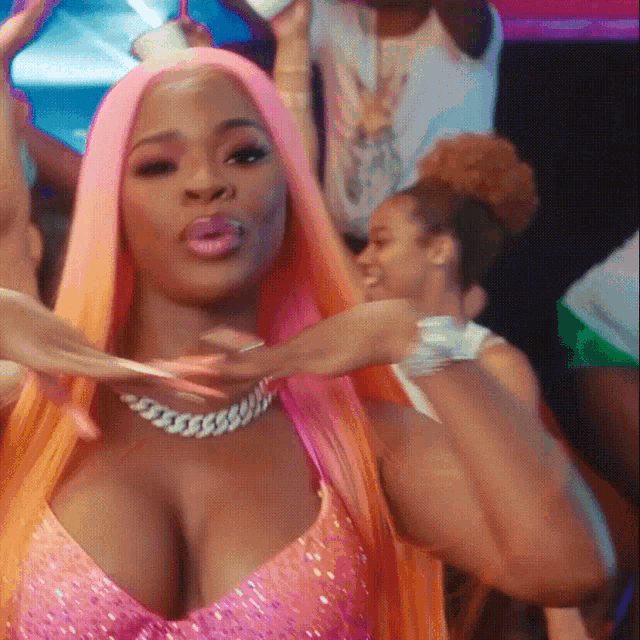 a woman with pink hair is wearing a pink top and a necklace