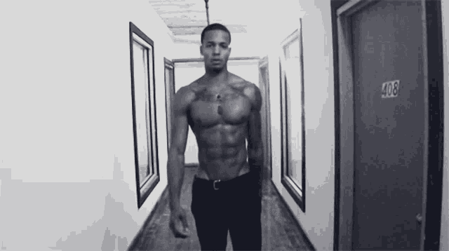 a shirtless man is standing in a hallway with the number 408 on the door