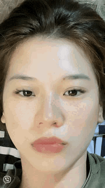 a close up of a woman 's face with a checkered shirt in the background