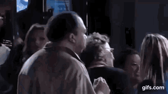 a man is smoking a cigarette in a dark room while another man looks on .