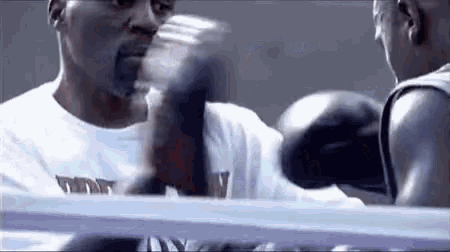 two men are boxing in a ring and one is wearing boxing gloves .