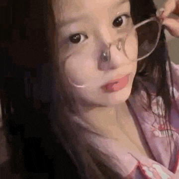 a young girl wearing glasses and a nose ring is making a funny face .