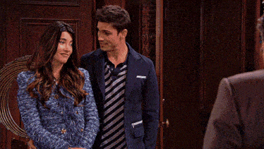 a man and woman standing next to each other in front of a door