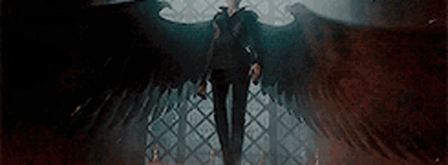 a man with wings is standing in a dark room with a sword .