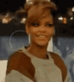 a woman is smiling and looking at the camera while wearing a brown and white sweater .